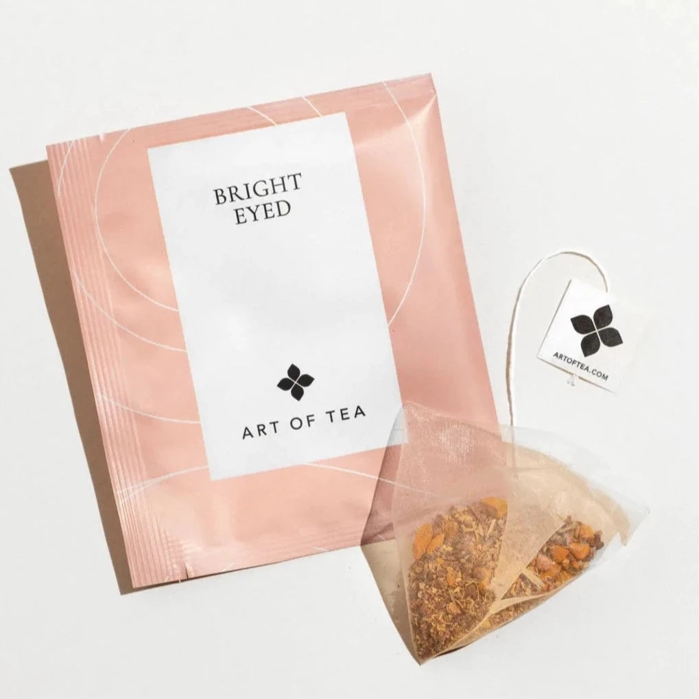 light pink tea sachet against white background with turmeric tea sachet next to it.