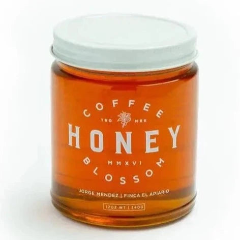 golden honey in glass jar with white lid. white text on the front that says "coffee blossom honey"