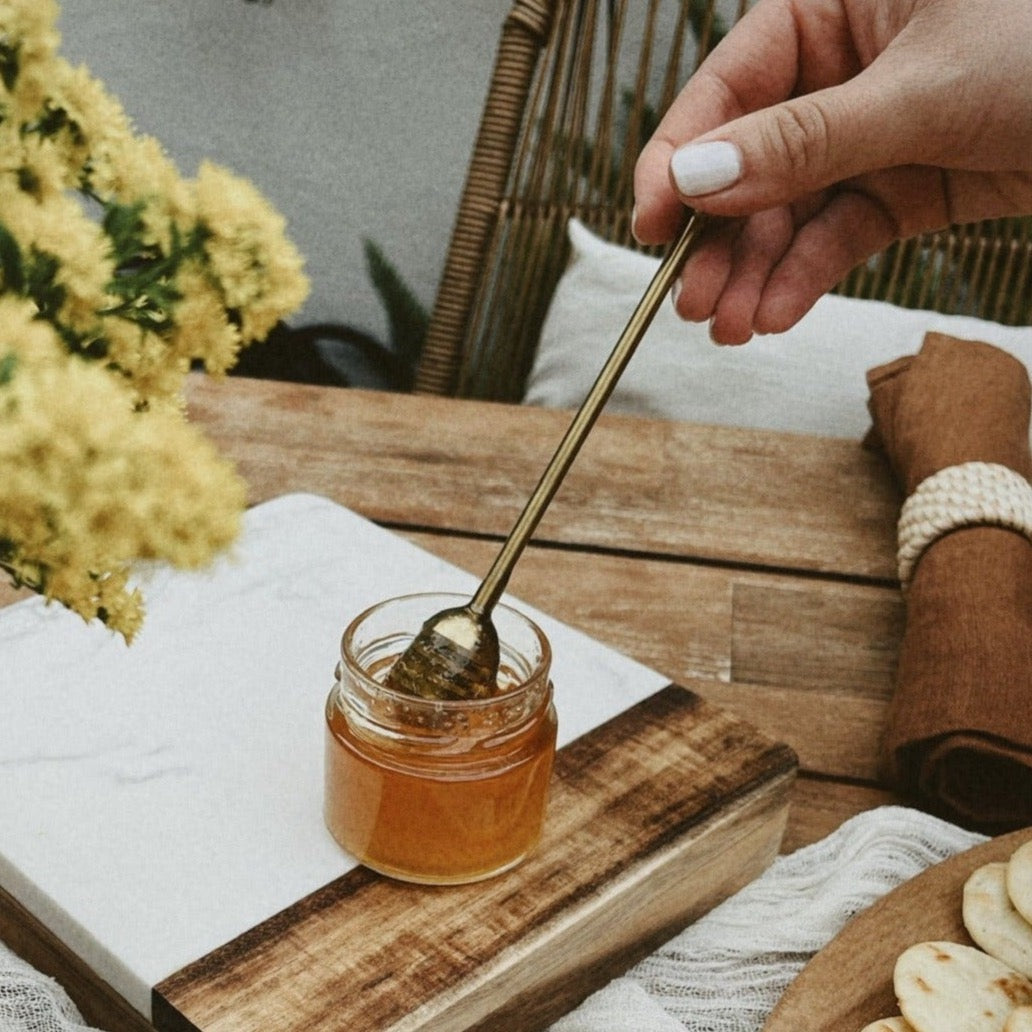 Honey dipper in honey pot on tablescape.