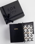 BOXFOX Black Matte Gift box with Black A6 Vegan Leather Notebook, black bullet pen, Goodio Sea Salt Chocolate Bar, and a single Copper Cow Pour Over Latte Packet